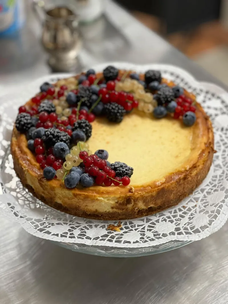 Runder Kuchen mit frischen Beeren auf einer Glasplatte